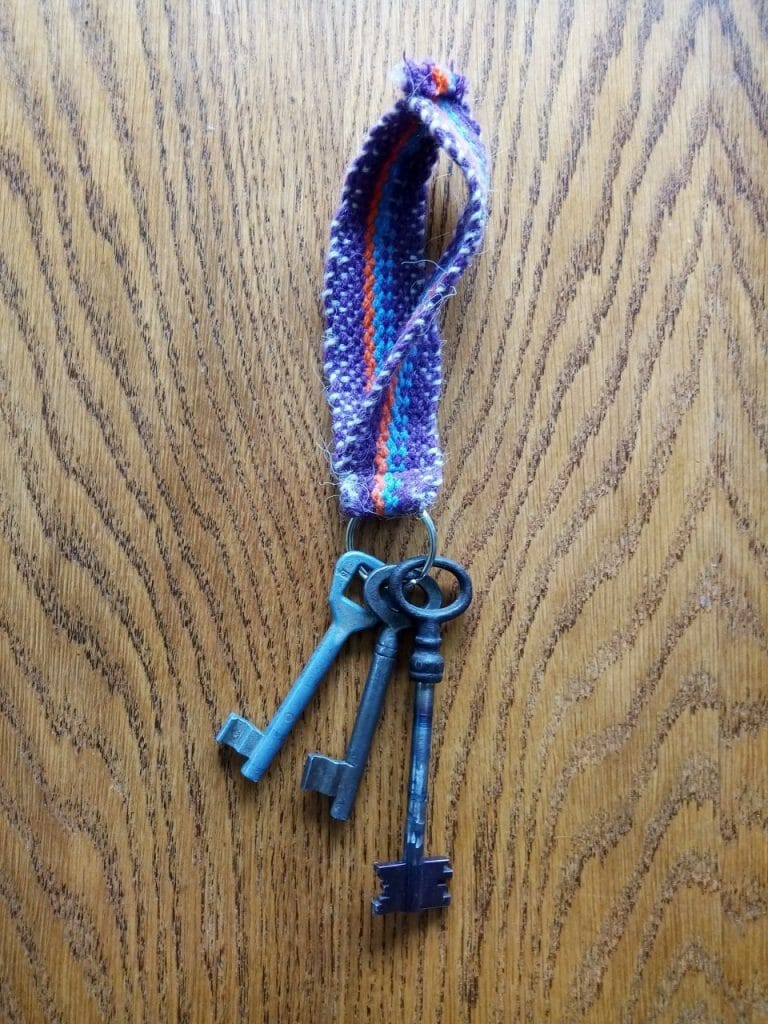 Klíčenka s pověšenými klíči vyrobena z ručně tkaného popruhu v Dílně Jinan